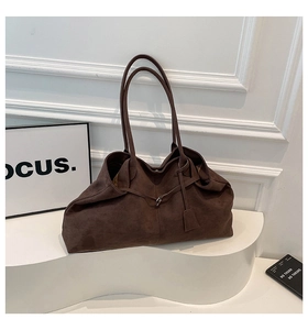 Détail du grand sac fourre-tout en daim marron foncé avec boucle et étiquette déco