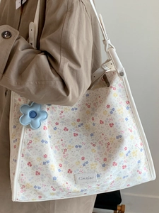 Floral canvas tote bag with white leather straps and blue flower charm accessory