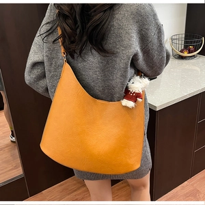 Detail of vintage orange hobo bag in textured leather with a cute plush bear charm