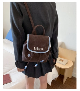Detail of dark brown suede backpack featuring blue star patches and NiKa embroidery