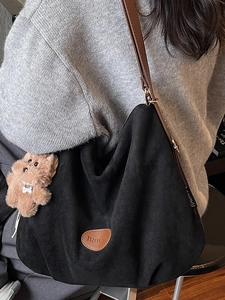 Chic black tote bag with brown leather straps and cute puppy charm on female model
