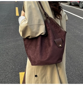 Détail macro du sac cabas en daim marron foncé avec coutures fines et boucle métal