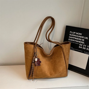Detail of brown suede tote bag with heart bear tassel charm and leather shoulder straps