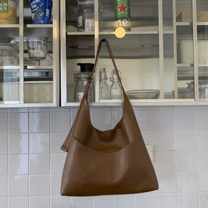 Detailed view of brown PU leather tote bag hanging on handle in minimalist kitchen