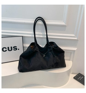 Détail du sac cabas en daim noir avec cordon de serrage sur un piédestal blanc