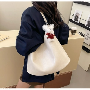 Minimalist beige tote bag with a cute white plush bear charm shown on model's shoulder