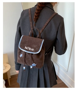 Detailed back view of vintage brown suede backpack with blue star patches and drawstring