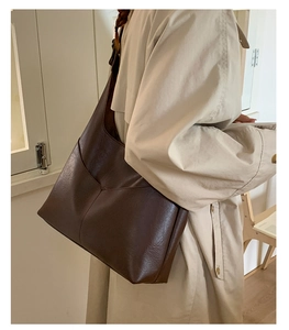 Detailed side view of a large dark brown vintage faux leather tote bag with V-shaped stitching