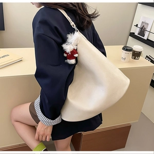 Gros plan sur un grand sac cabas beige avec un porte-clé peluche chien et texture douce