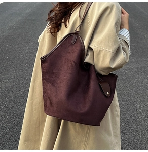 Détail du sac cabas en daim marron foncé avec fines lanières et boucles métalliques dorées