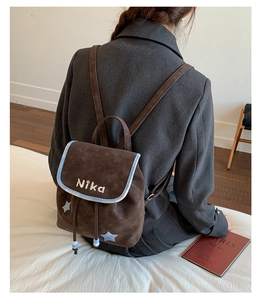 Detailed macro of brown suede backpack showing the star pattern and NiKa embroidery