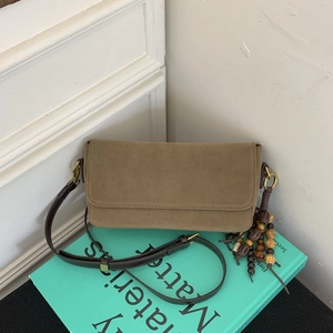 Detail of khaki suede crossbody bag with vintage wooden bead charm and brown leather strap