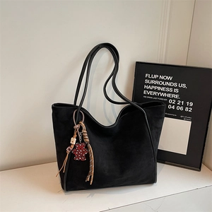 Detail of black faux suede tote bag with leopard heart bear charm and woven strap
