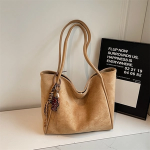 Detail of camel suede tote bag with fringe tassel and small red pattern bear charm