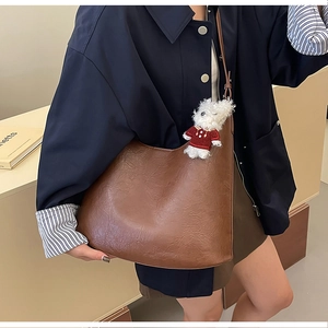 Détail d'un grand sac bandoulière marron en similicuir avec un joli pendentif chien peluche