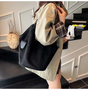 Détail d'un grand sac cabas en daim noir porté par un mannequin en trench-coat
