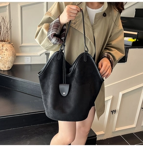 Vue détaillée d'un grand sac cabas en daim noir porté avec une bandoulière fine