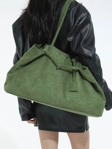 Grand sac cabas en daim vert avec boucle en T porté par un mannequin en veste de cuir