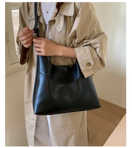 Close-up of black retro textured leather tote bag on model's shoulder with trench coat