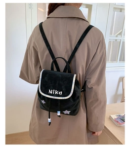 Model wearing a black velvet backpack with Nika embroidery and purple star detail