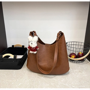 Détail du sac cabas en similicuir marron à texture de litchi avec pendentif chien