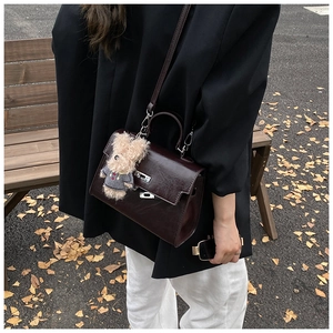 Detail view of burgundy Kelly handbag with silver hardware and cute brown bear charm