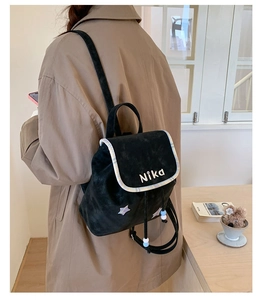 Detail view of black suede drawstring backpack with Nika logo and star pattern