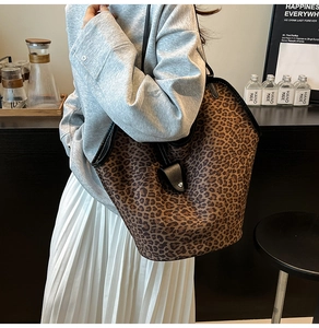 Vue détaillée du sac cabas léopard avec bordures noires et lanières en cuir sur modèle
