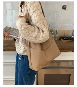 Close-up of minimalist beige PU leather tote bag with V-shaped pocket in lifestyle setting