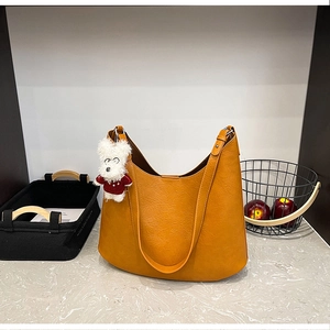 Détail du sac hobo vintage caramel avec texture grainée et charmant pendentif chien peluche