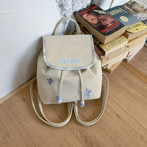 Detail of off-white backpack with blue NiKa embroidery and star patches in college style