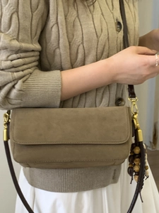 Minimalist taupe suede baguette bag with a slim leather strap and wood bead detail