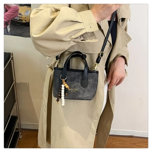 Detailed view of dark grey canvas tote bag with leather straps and retro wooden bead charm
