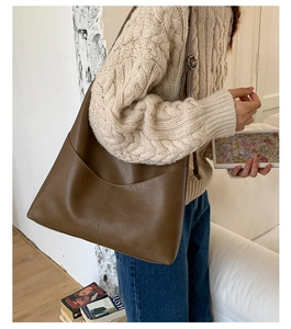 Detail showing the retro brown leather tote bag with curved front pockets on a model