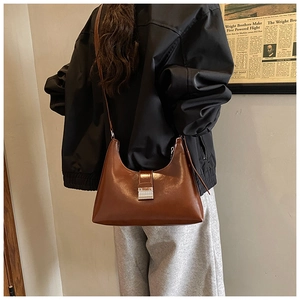 Detailweergave van de vintage donkerbruine crossbodytas met zilveren gesp op een model