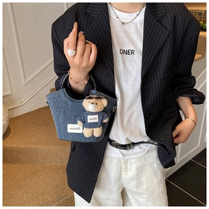 Détail du mini sac seau en jean bleu avec poignée croco et breloque ours en peluche