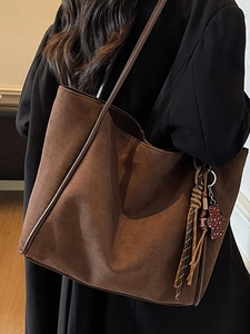 Retro brown suede tote bag for women with tassel charm shown on shoulder for commuting