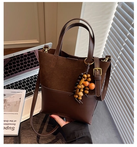 Detail of retro dark brown tote bag with suede texture and wooden bead pendant accessory