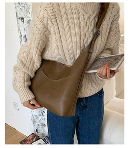 Detail of khaki brown PU leather shoulder bag with smooth curves and silver metal buckle