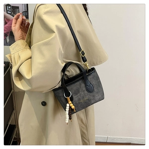 Detail of grey matte canvas bag with black leather straps and decorative wooden beads