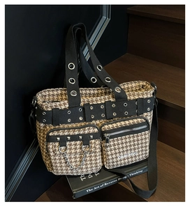 Detail of retro houndstooth tote bag with punk rivets and chains on wooden stairs