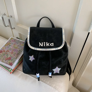 Detail of black velvet backpack showing plaid star patch and blue beaded drawstring