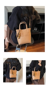 Detail view of a brown leather bag with suede patchwork and retro wooden bead pendant