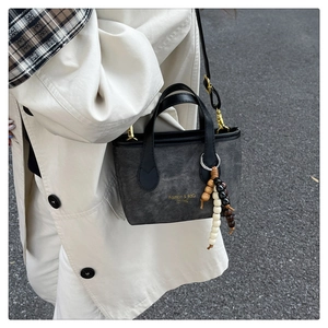 Detail of dark grey canvas bucket bag with leather handles and wood bead tassel