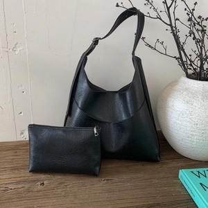Detail of black PU leather hobo bag set with vintage texture on a rustic wooden table