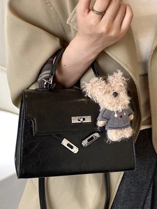 Minimalist black shiny leather trapezoid handbag with metal lock and cute teddy bear charm