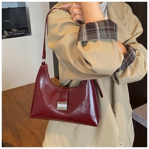 Detail van de bordeaux hobo tas met rechthoekige metalen gesp en glanzende leertextuur