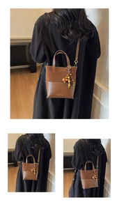 Detail of suede and leather contrast bucket bag with stylish wooden bead charm