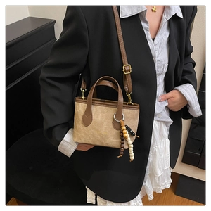 Detail of tan suede mini tote bag with adjustable strap and vintage beaded charm