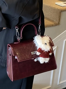 Chic burgundy leather top-handle bag with a cute plush bear charm in a classic design